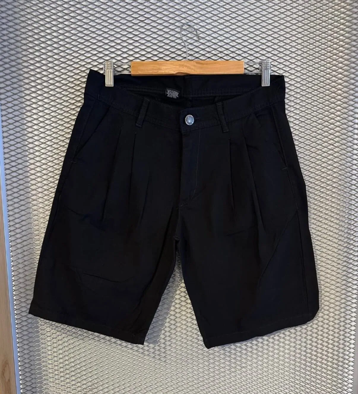 Bermuda de gabardina negra colgada en percha, foto de producto